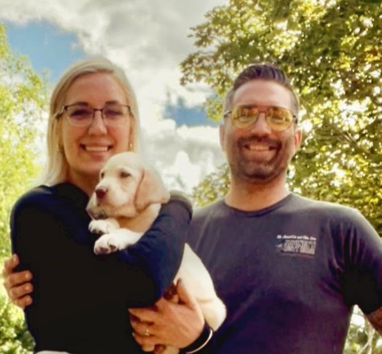 Gina with her husband Nick holding their yellow lab puppy